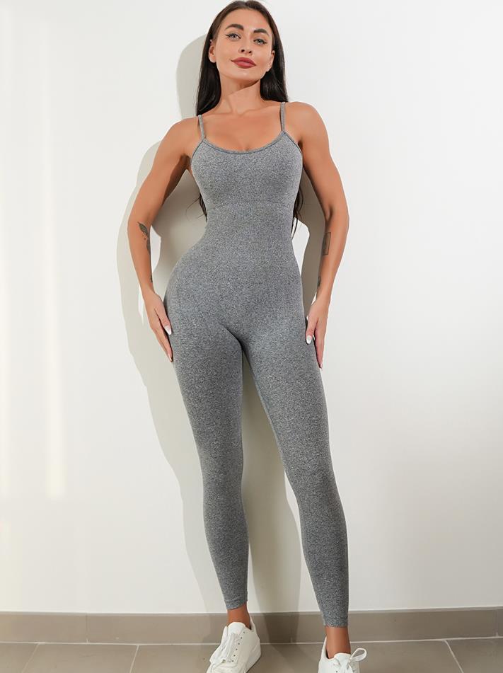 Woman wearing a gray jumpsuit against a white wall