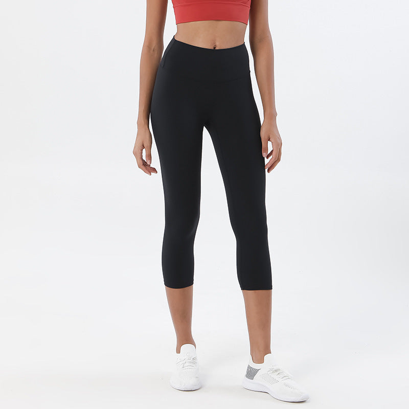 Person wearing black capri leggings with a red top on a white background