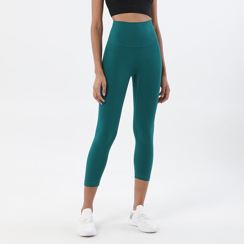 Person wearing teal leggings and white sneakers on a white background