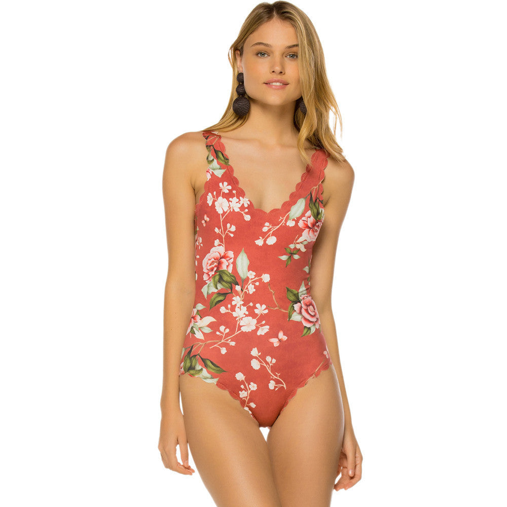 Woman wearing a red floral one-piece swimsuit on a white background