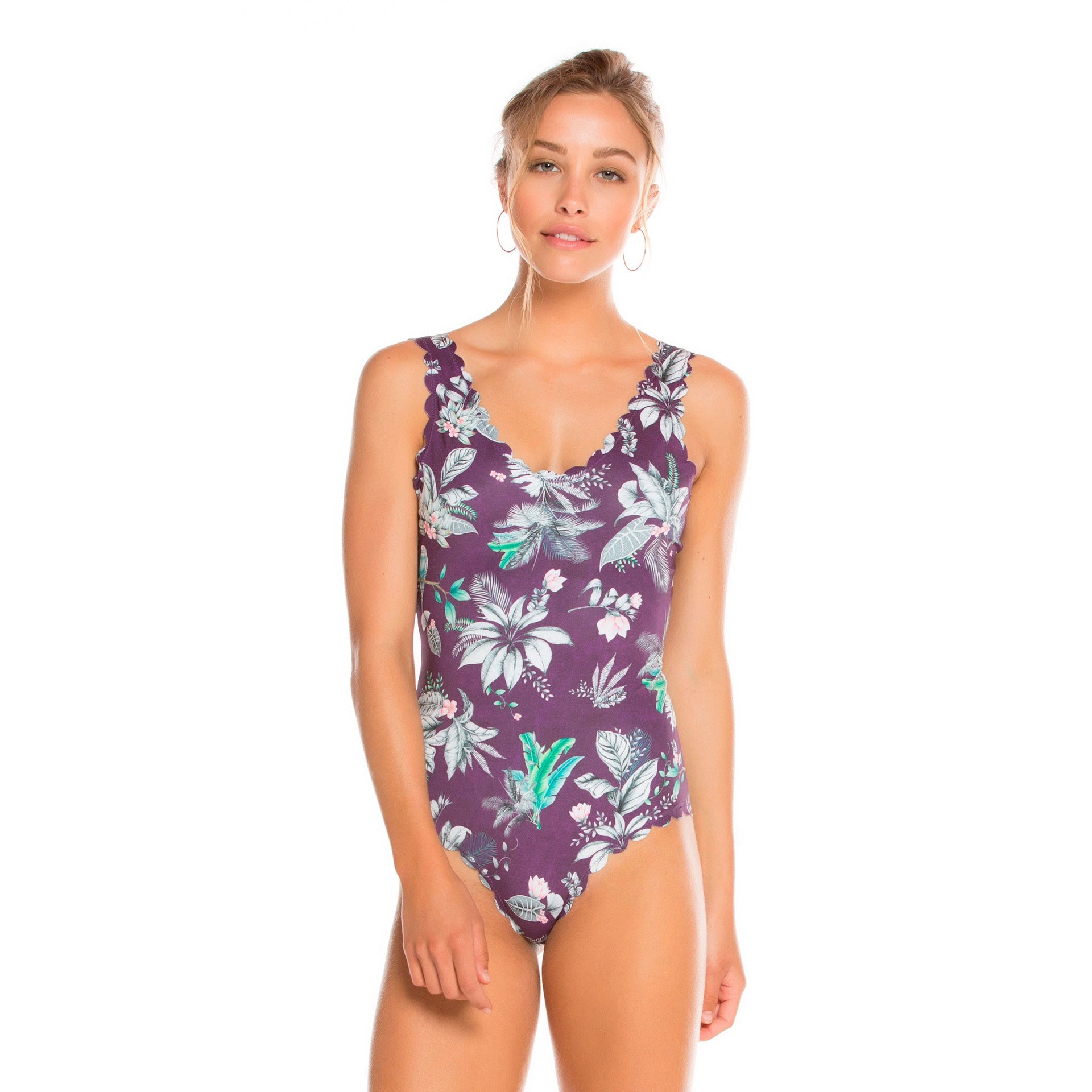 Woman wearing a floral-patterned purple swimsuit on a white background