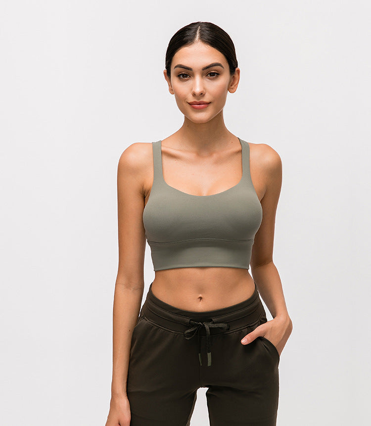 Woman wearing a green sports bra and black pants on a light gray background