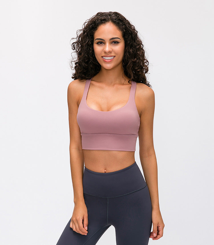 Woman wearing a pink sports bra and dark gray leggings on a light gray background