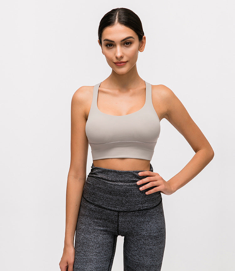 Woman wearing a beige sports bra and gray leggings on a light gray background