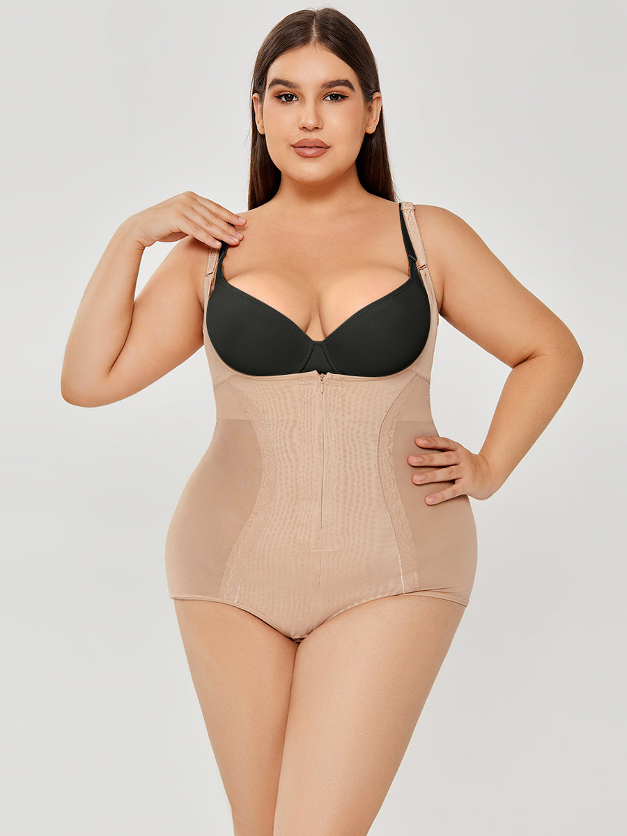 Woman wearing a beige shapewear bodysuit over a black bra on a light gray background