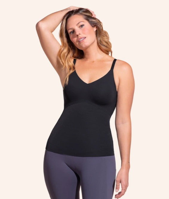 Woman wearing a black tank top and gray leggings on a white background
