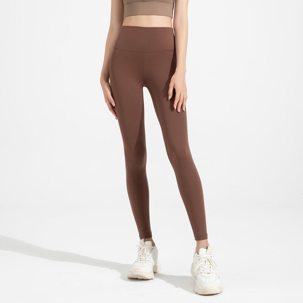 Person wearing brown leggings and white sneakers on a light gray background
