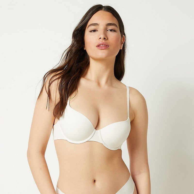 Woman wearing a white bra against a plain background