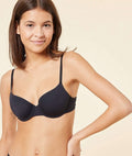 Woman wearing a black bra against a beige background