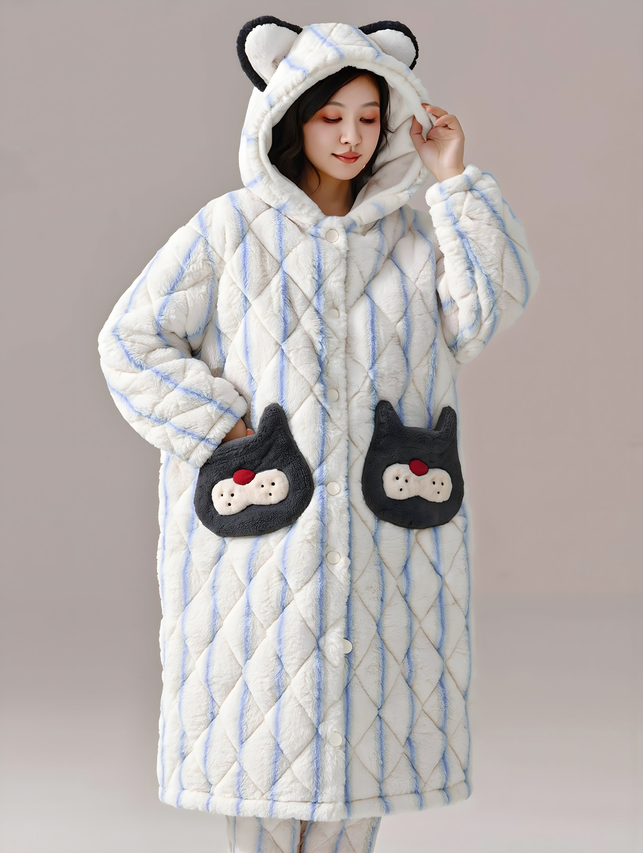 Person wearing a quilted coat with cat ears and paw pockets on a plain background