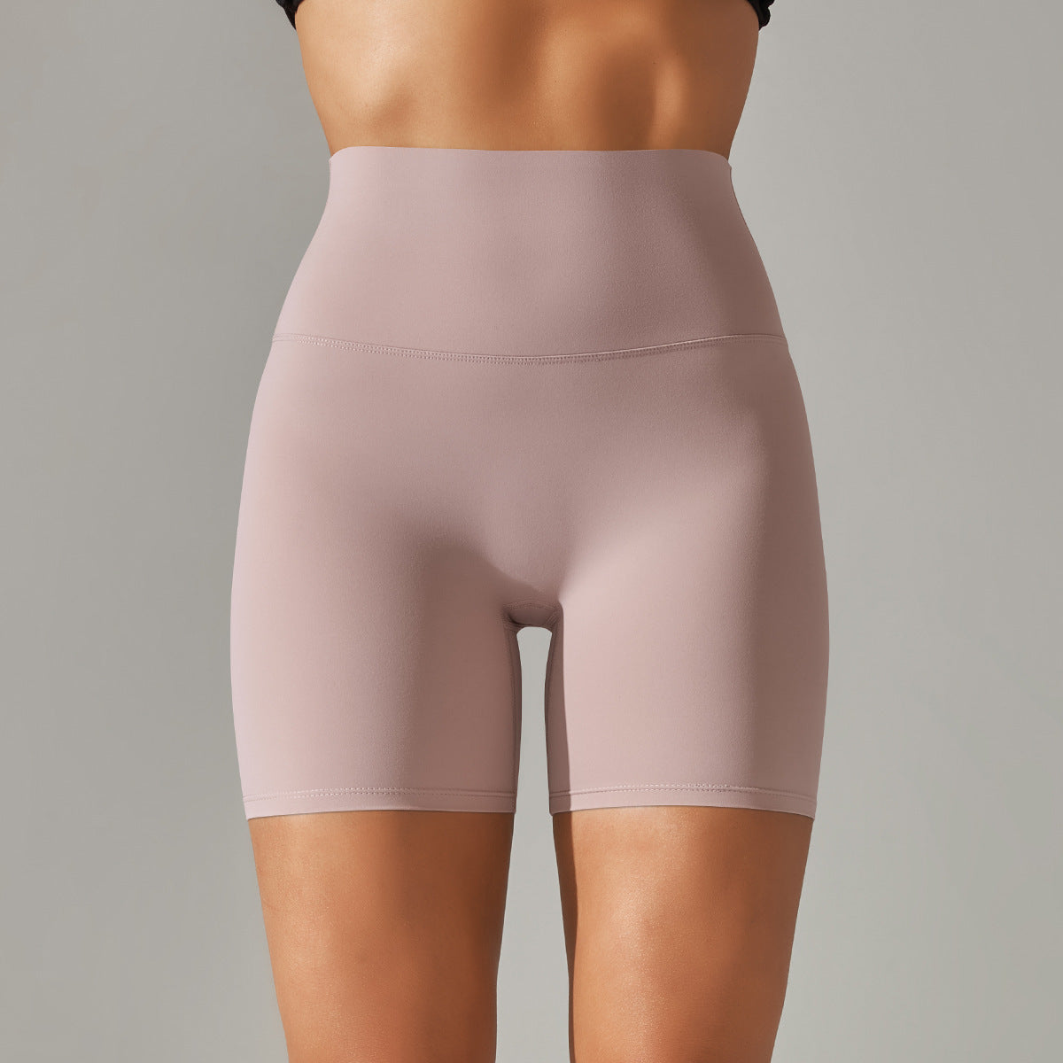 Pink high-waisted shorts worn by a person on a gray background