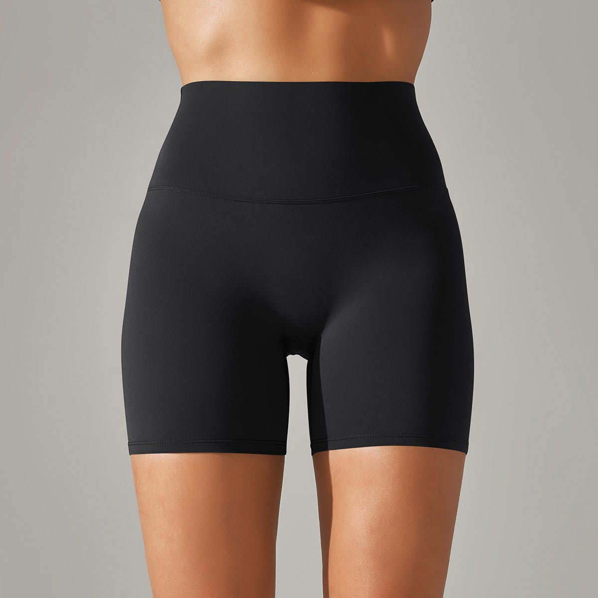 Black high-waisted shorts worn by a person on a gray background