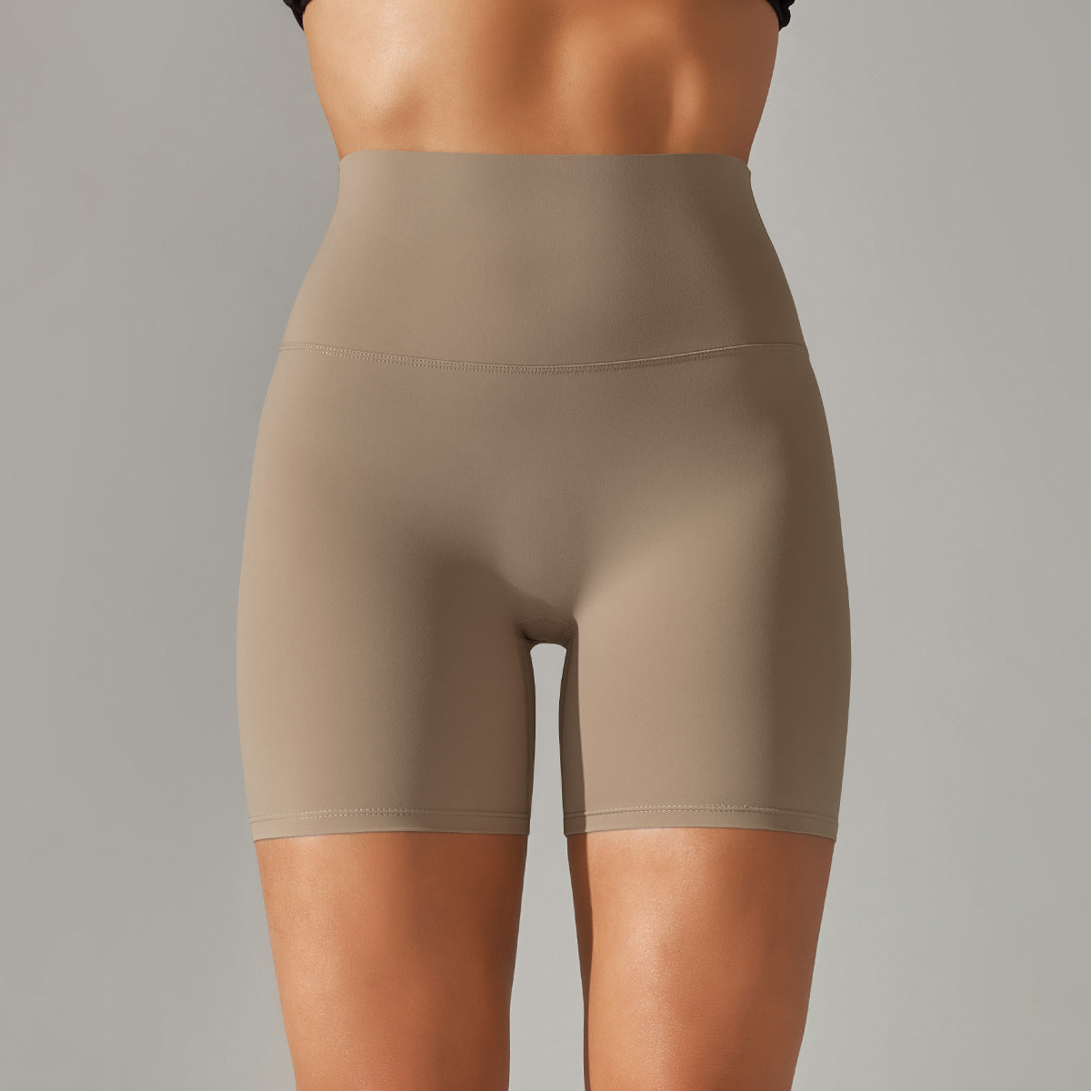 Beige high-waisted shorts worn by a person on a gray background