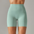 Mint green athletic shorts worn by a person on a gray background