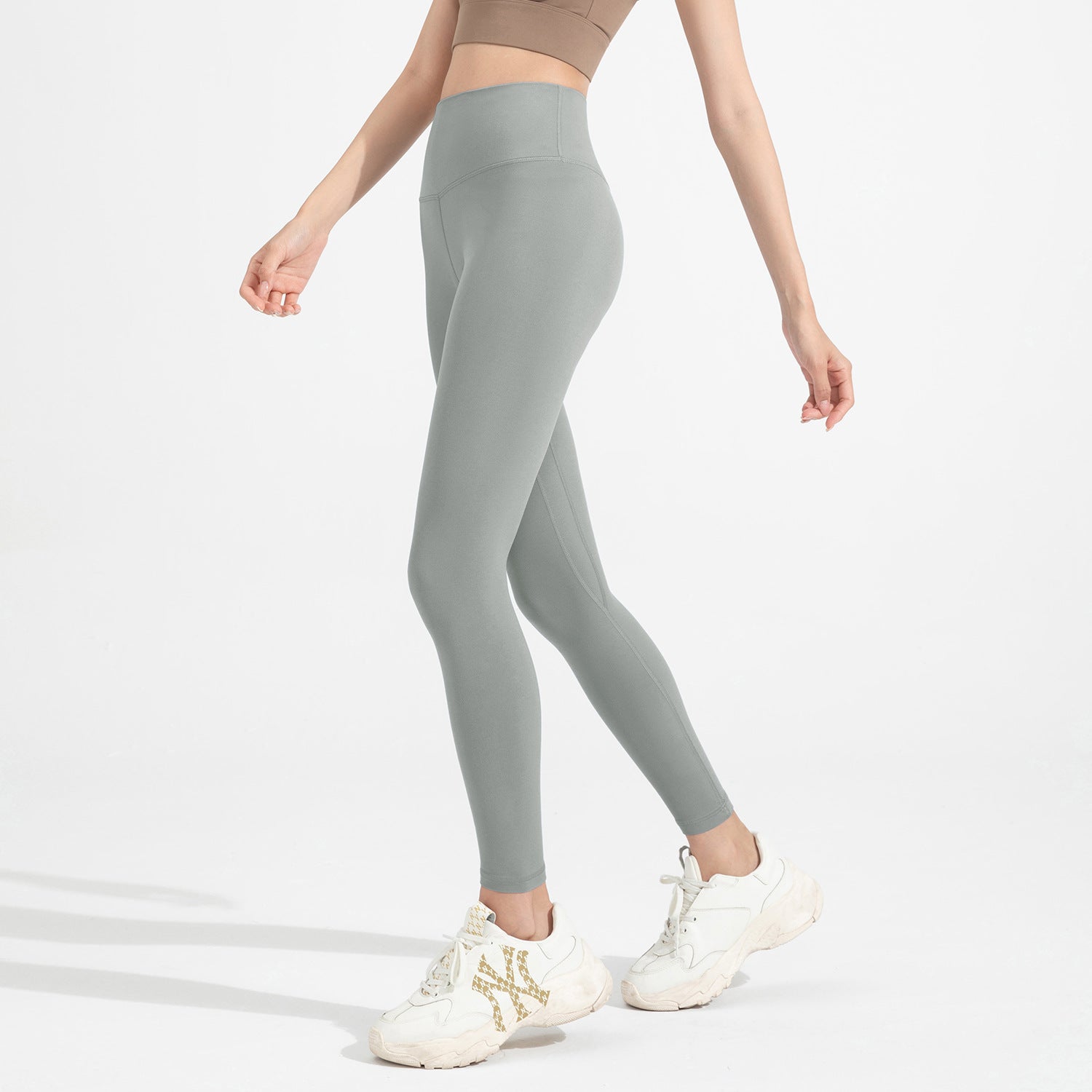 Person wearing gray leggings with a plain background