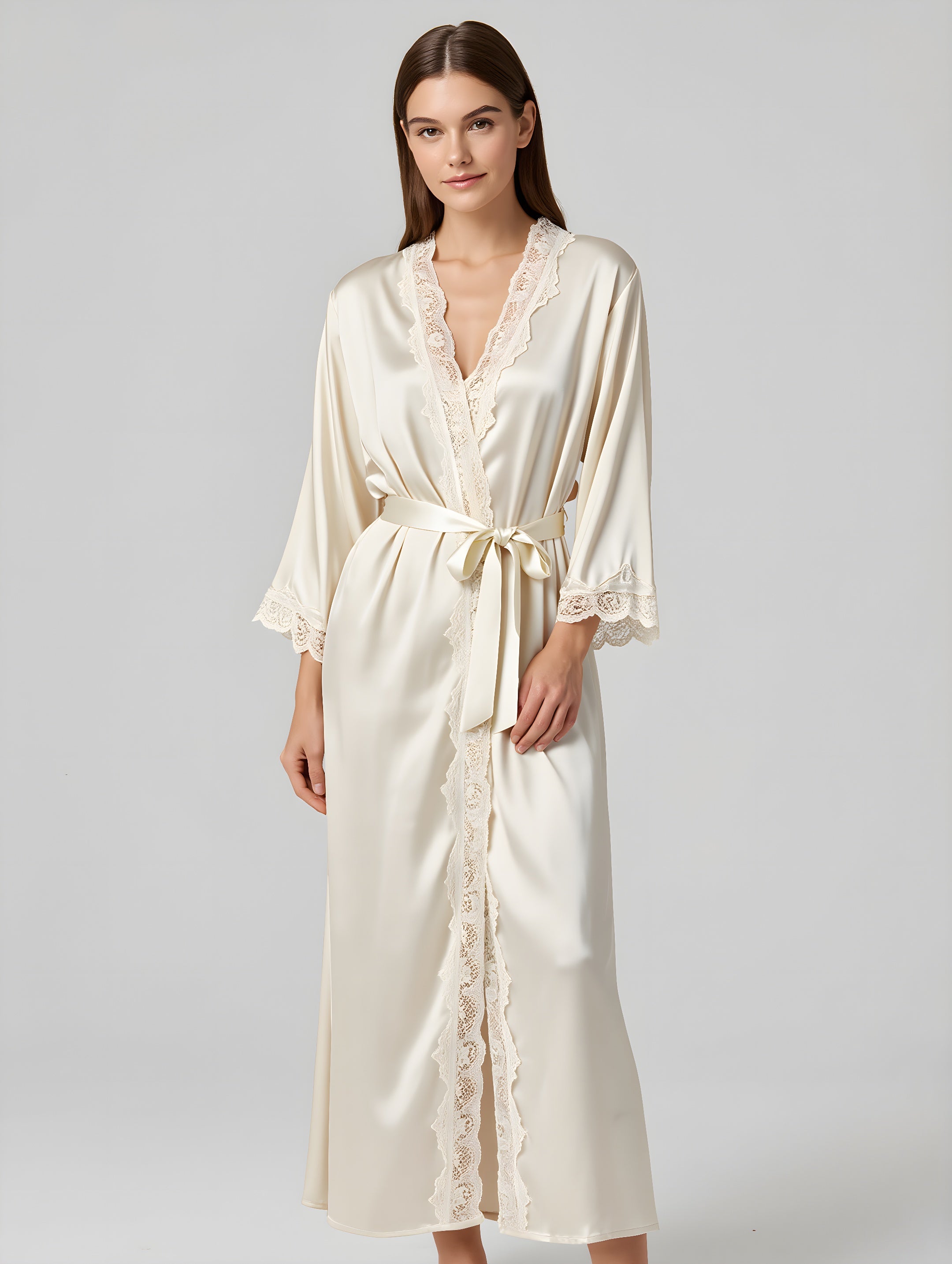 Woman wearing a cream satin robe with lace trim on a gray background