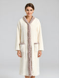 Woman wearing a long, cream-colored robe with fur trim on a gray background