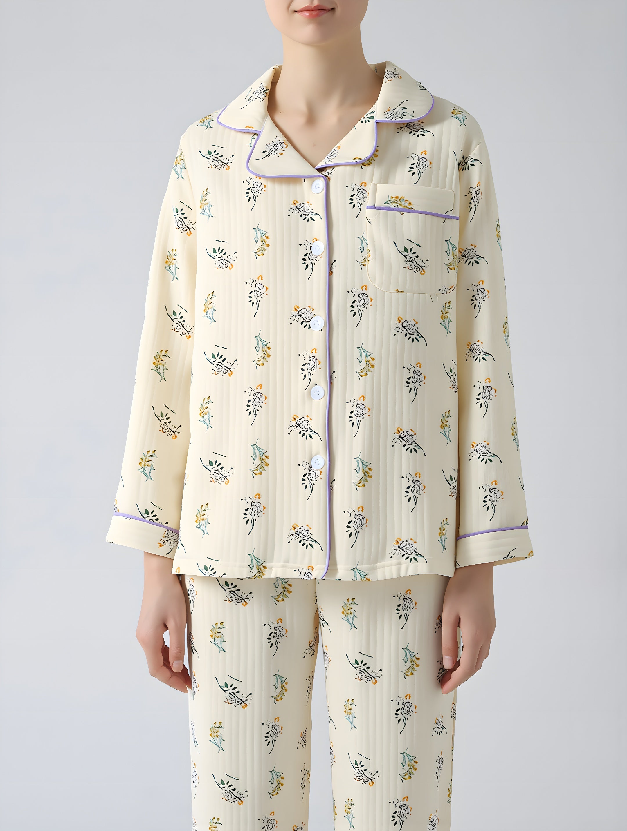 Person wearing a cream-colored pajama set with floral patterns on a plain background