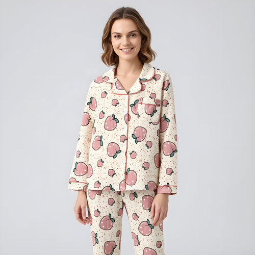 Woman wearing a pajama set with pink apple pattern on a light gray background