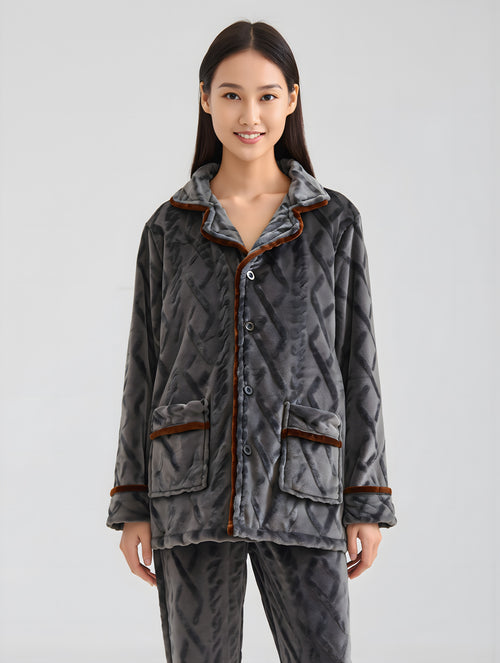 Woman wearing a gray quilted jacket with brown trim on a light gray background