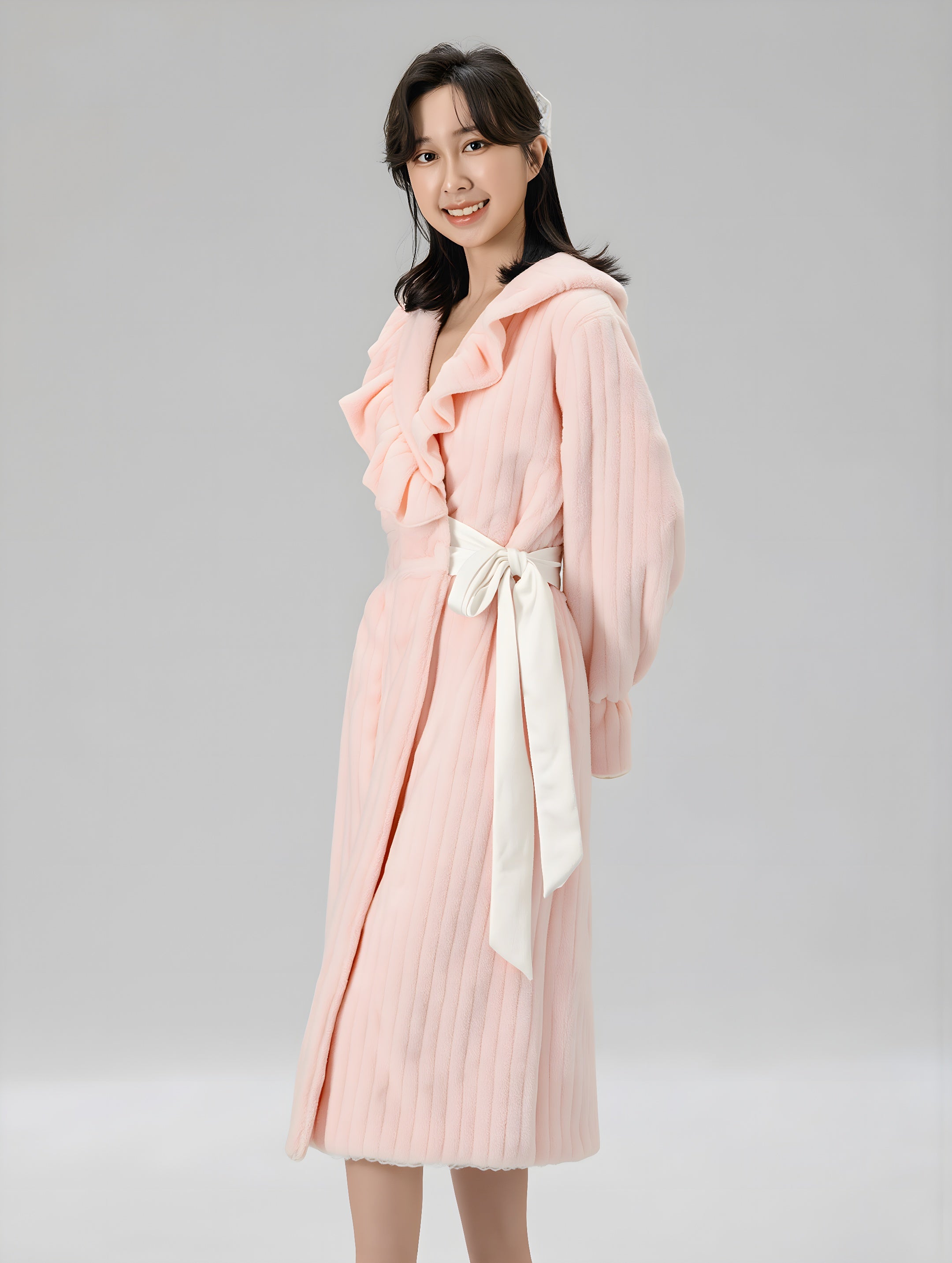 Woman wearing a pink robe with a white belt on a gray background