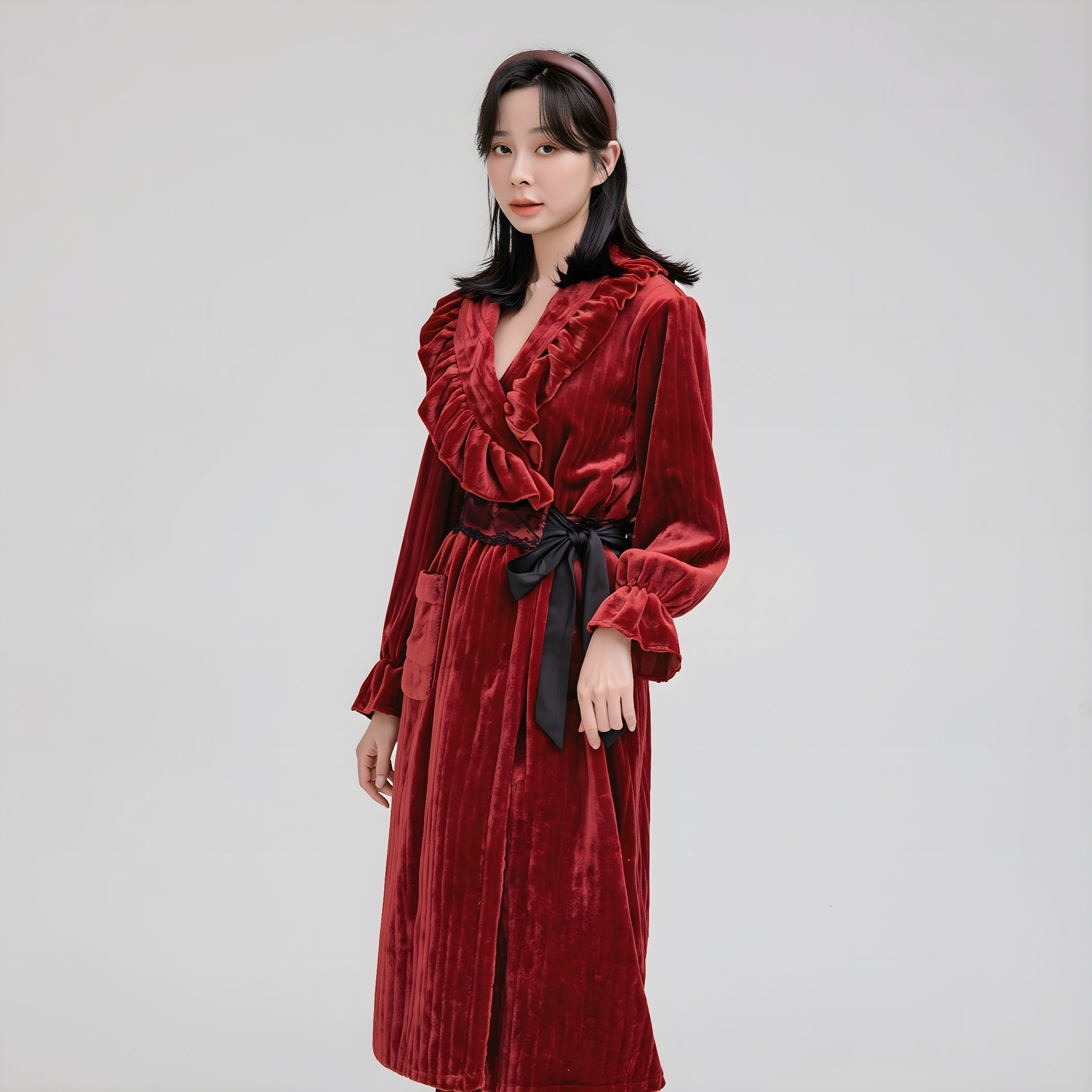 Woman wearing a red velvet dress with a black belt on a gray background